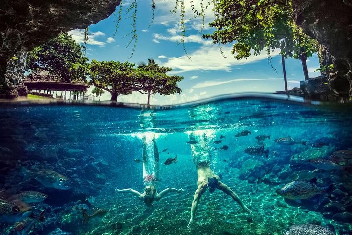 Underwater view of two people in the crystal clear waters of Piula Cave Pool.